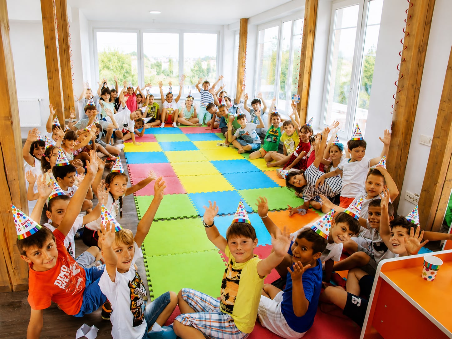 Grup de copii cu coifuri de petrecere, salutând veseli la un eveniment